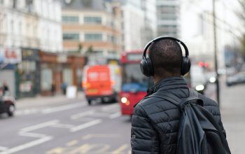 Back-view of a man with headphones looking out at a blurry street